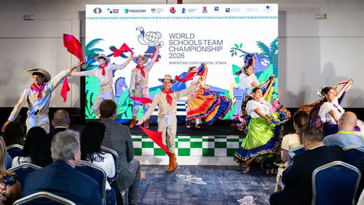 Costa Rican folk dance group performing at the opening ceremony, in front of the World Schools Team Championship 2026 backdrop