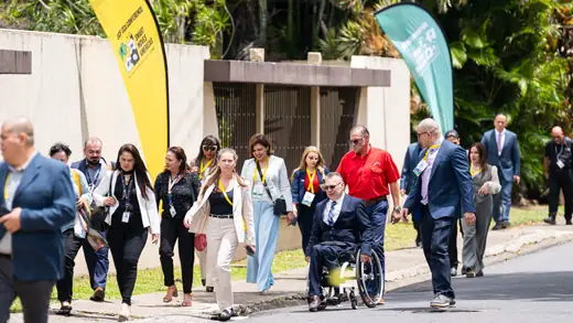 Participants, among them a delegate using a wheelchair, walking to the conference venue