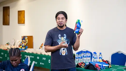 Sergio showing one of his carved and painted masks to the children