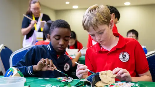 Two players painting a carved mask
