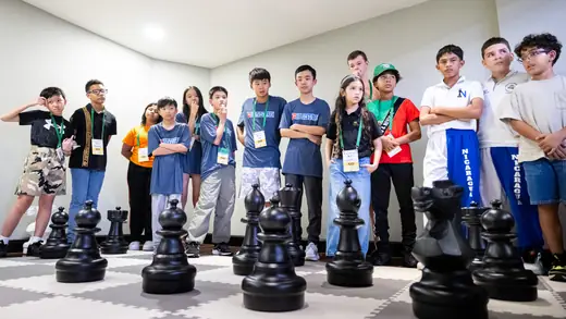 Young players gathered around the oversized pieces